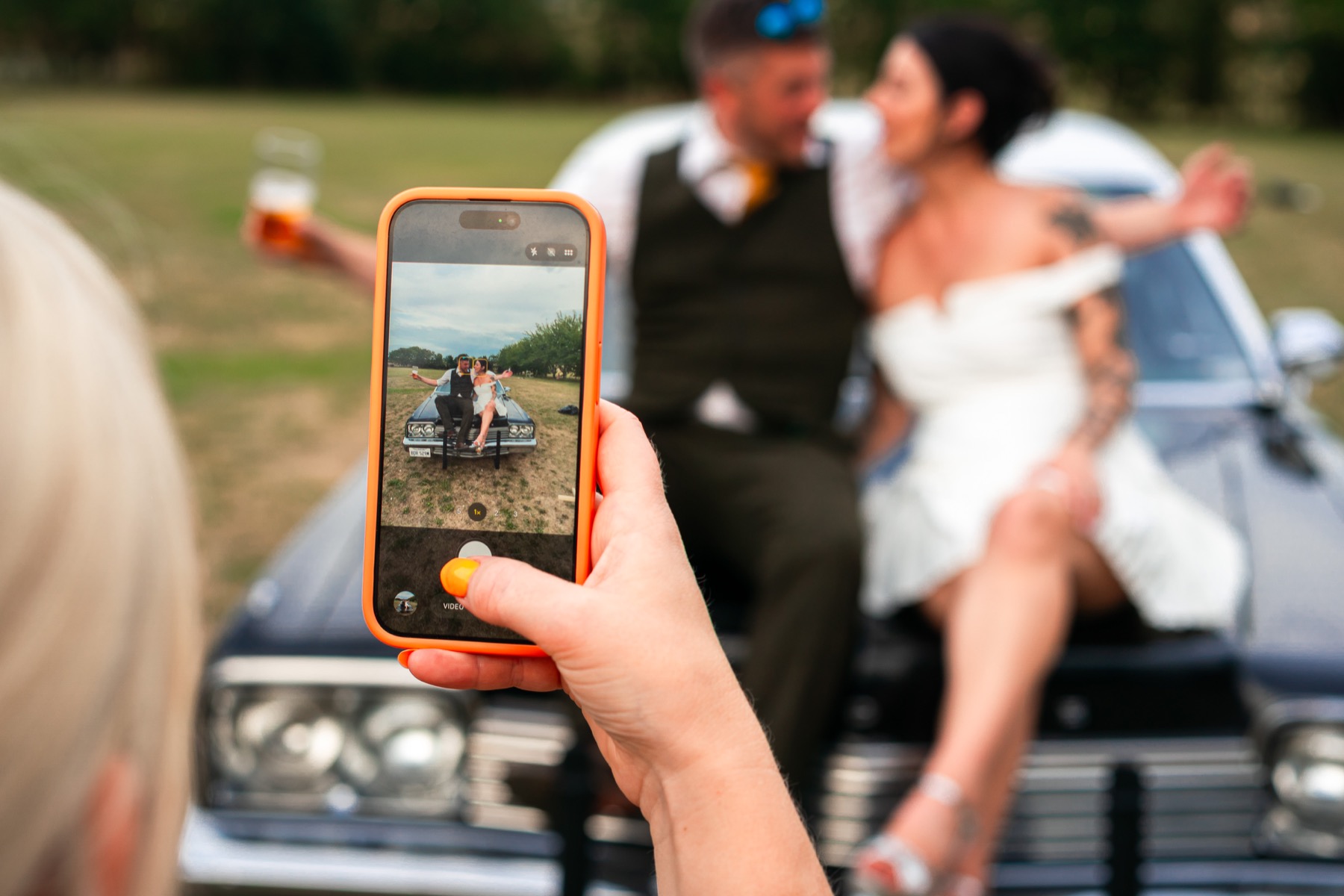 A wedding guest films the newlyweds posing together on the Bluesmobile