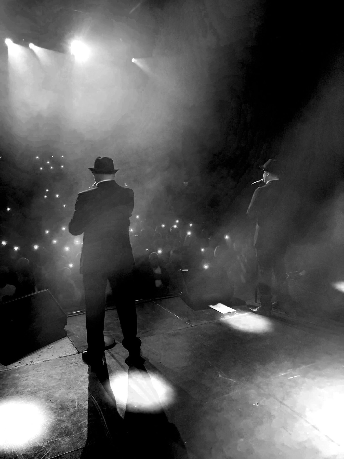View from the stage towards a theatre audience holding up phone lights