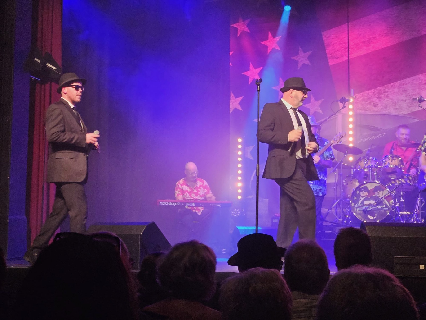 Jake and Elwood performing under theatre stage lighting