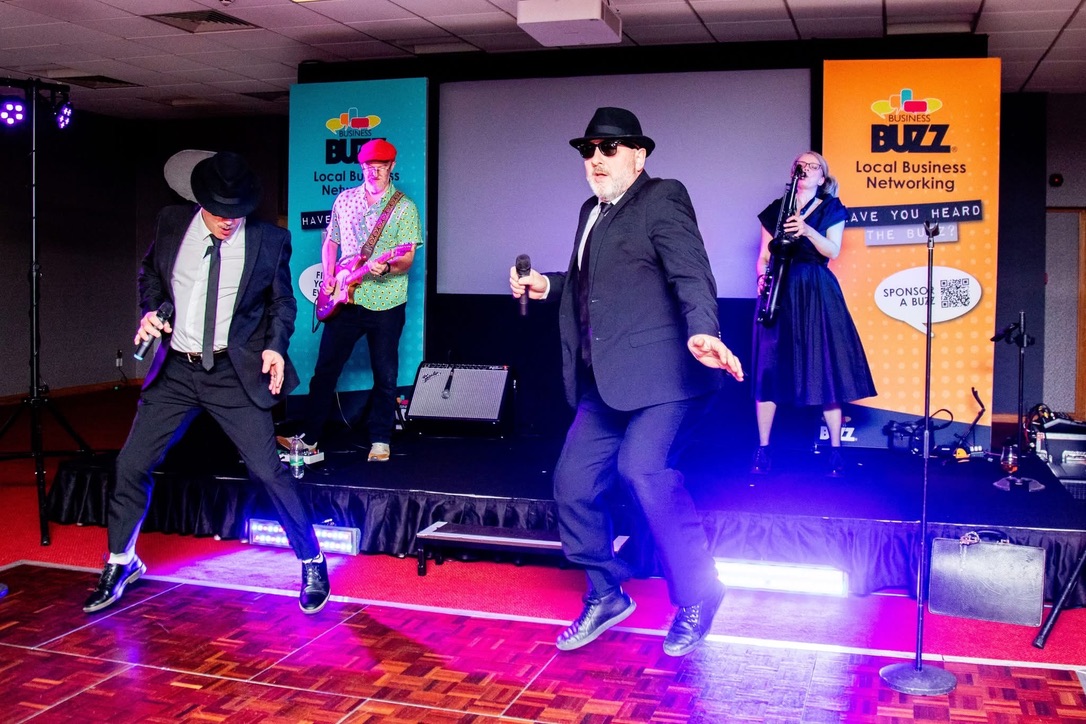 The four-piece band performing live with guitar and saxophone
