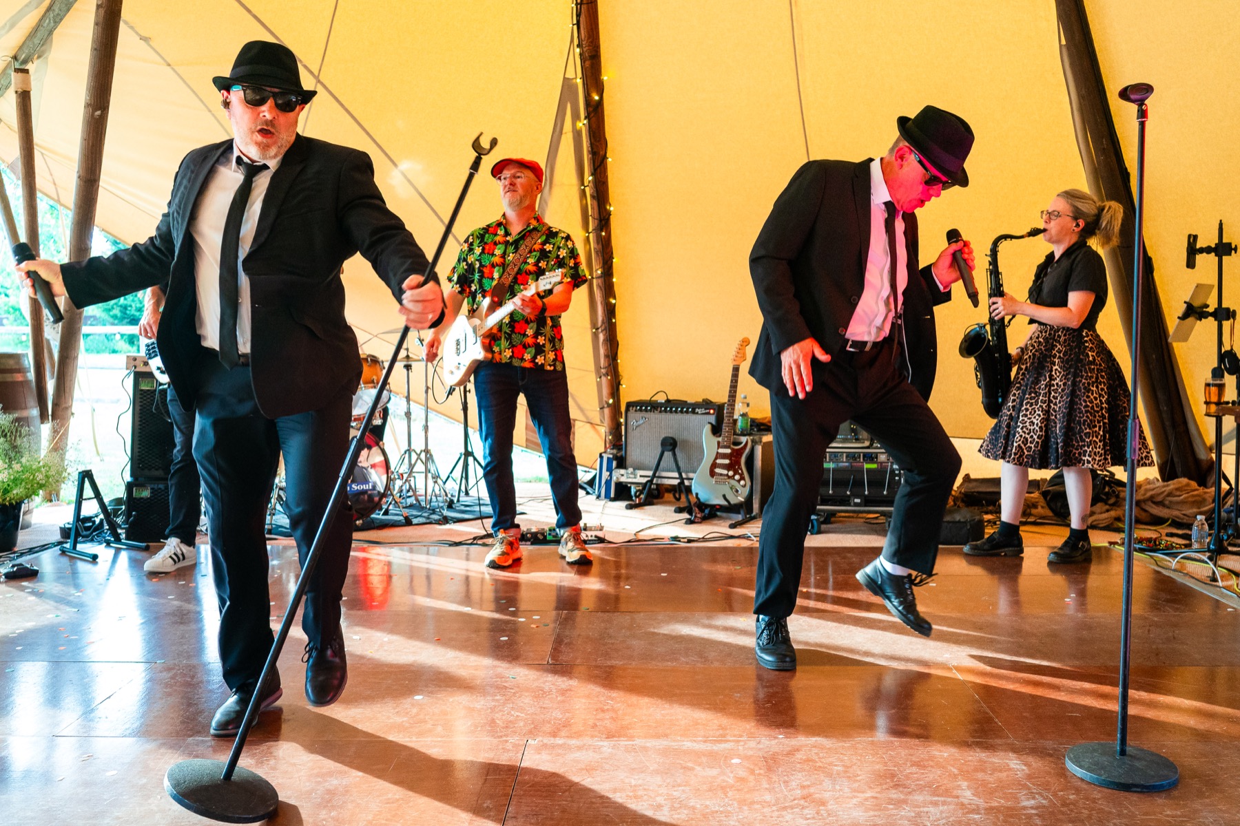 The full band performing an energetic routine together at a marquee wedding